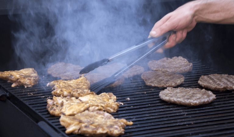 BBQ Grill with chicken and burgers on tongs