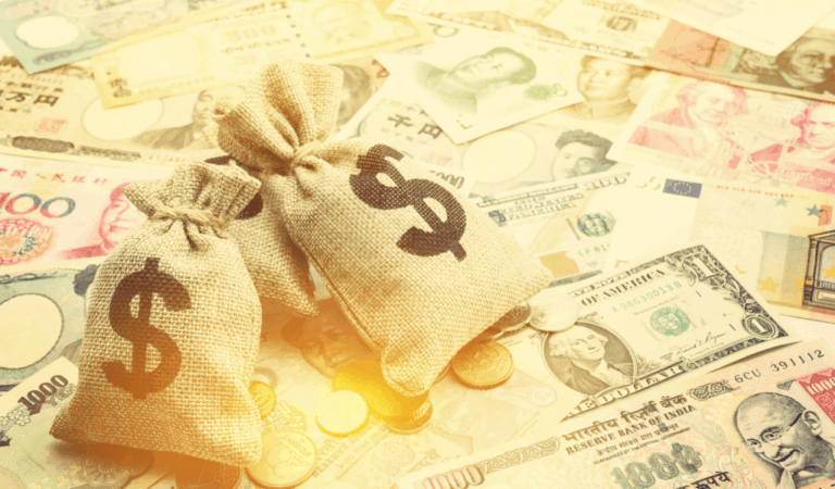 Bags of gold with dollar signs on them, sitting on varying global currencies.