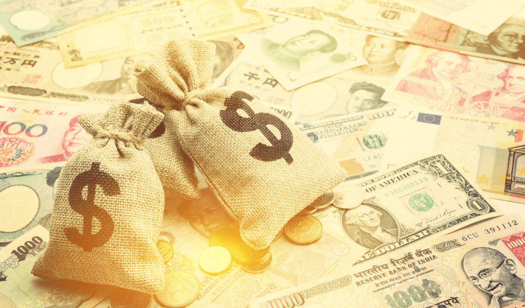 Bags of gold with dollar signs on them, sitting on varying global currencies.